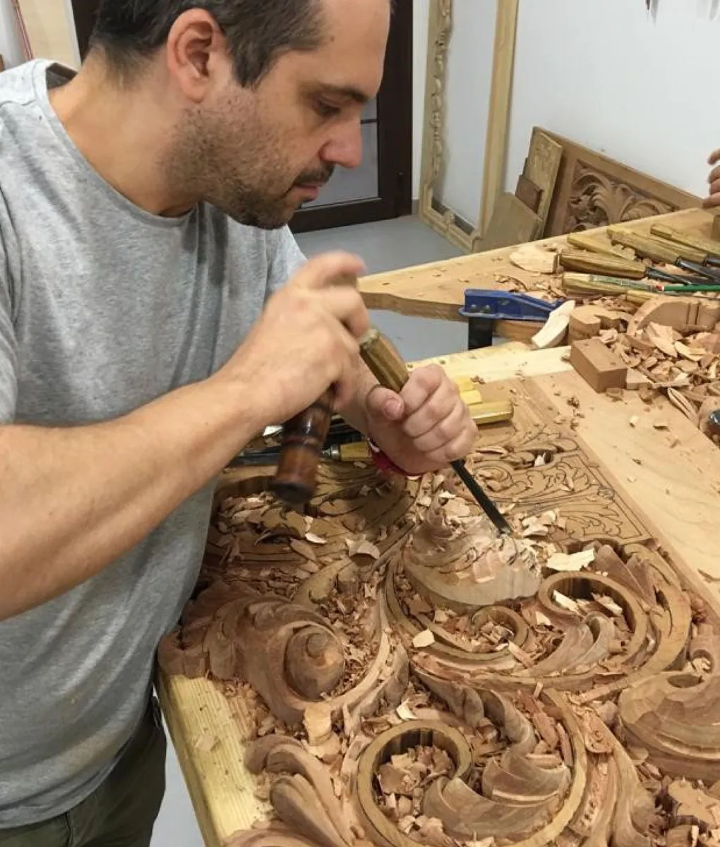 Tallista trabajando con gubia una talla ornamental en madera