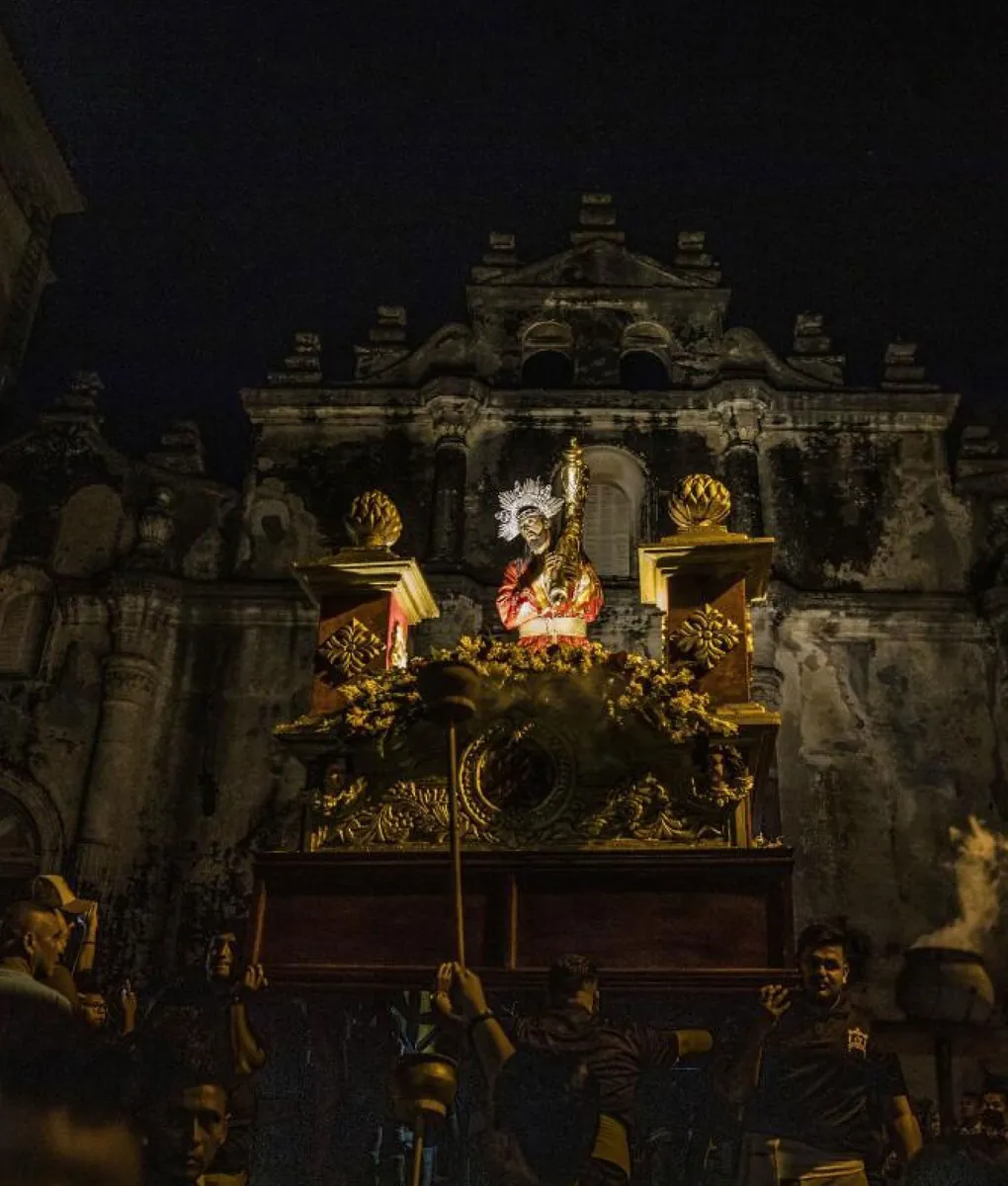 Paso procesional iluminado de noche ante una fachada barroca